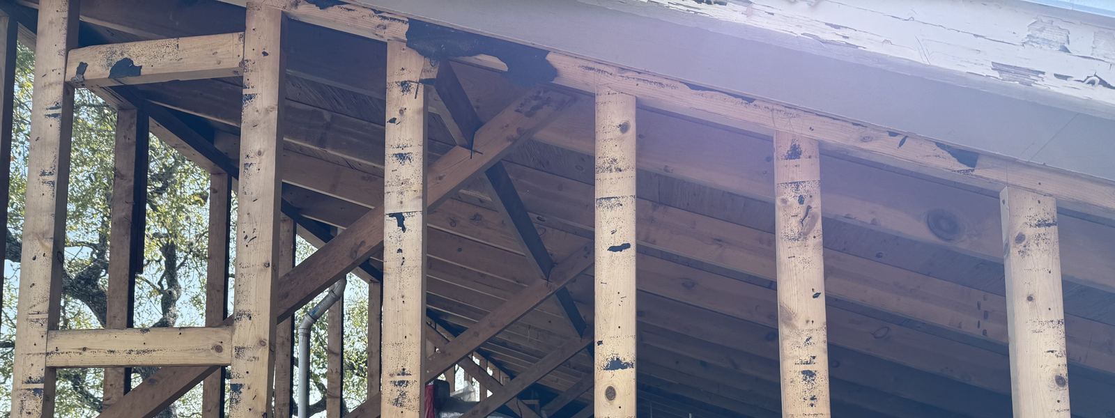 Open attic framing with the old roof deck visible between the rafters